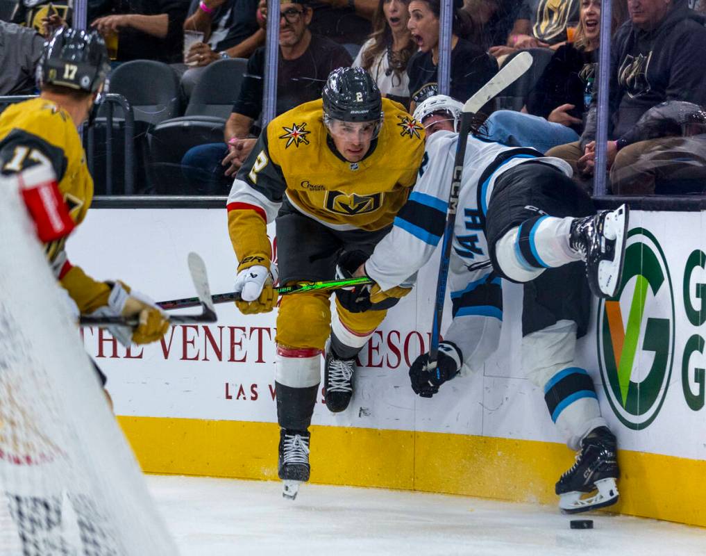 Golden Knights defenseman Zach Whitecloud (2) checks Utah Hockey Club forward Logan Cooley (92) ...