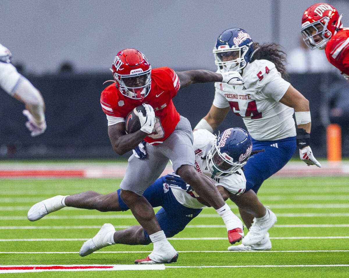 UNLV running back Jai'Den Thomas (9) breaks a tackle attempt by Fresno State Bulldogs defensive ...