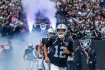 Raiders quarterback Aidan O'Connell (12) and teammates run onto the field from the tunnel befor ...