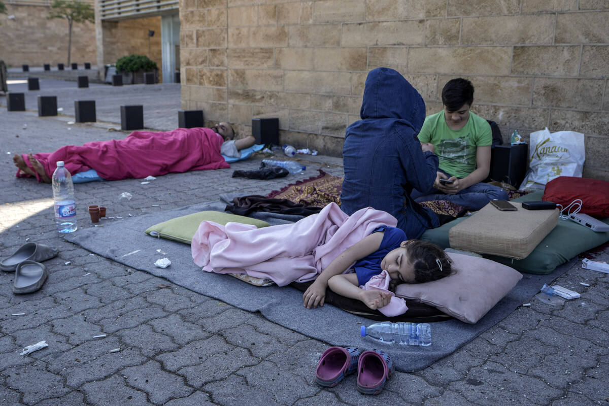 A family sleep on the ground in Beirut's corniche area after fleeing the Israeli airstrikes in ...