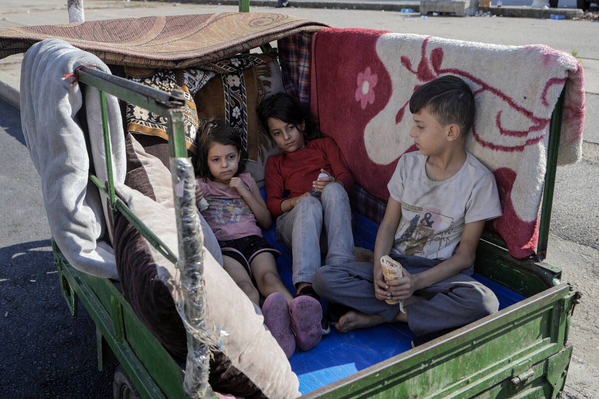 Children sit in a motorcycle cart in Beirut's Martyrs' square after fleeing the Israeli airstri ...