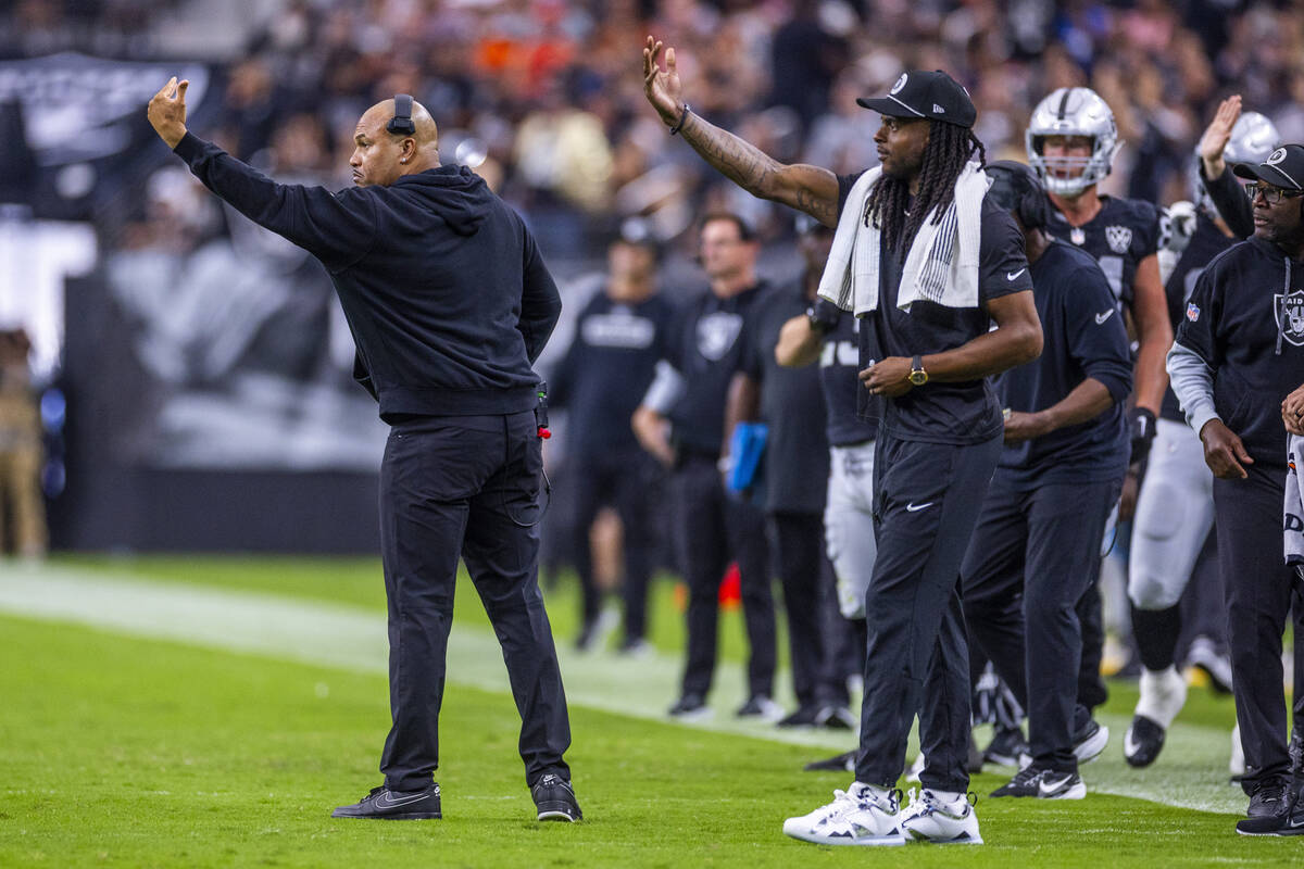 Raiders Head Coach Antonio Pierce and wide receiver Davante Adams (17) signal players on the fi ...