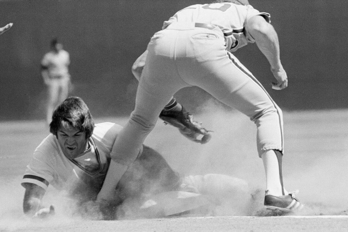 Cincinnati Reds runner Pete Rose knocks the bag loose as he goes headfirst under the tag attemp ...