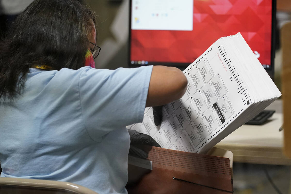 A county election worker scans mail-in ballots at a tabulating area at the Clark County Electio ...