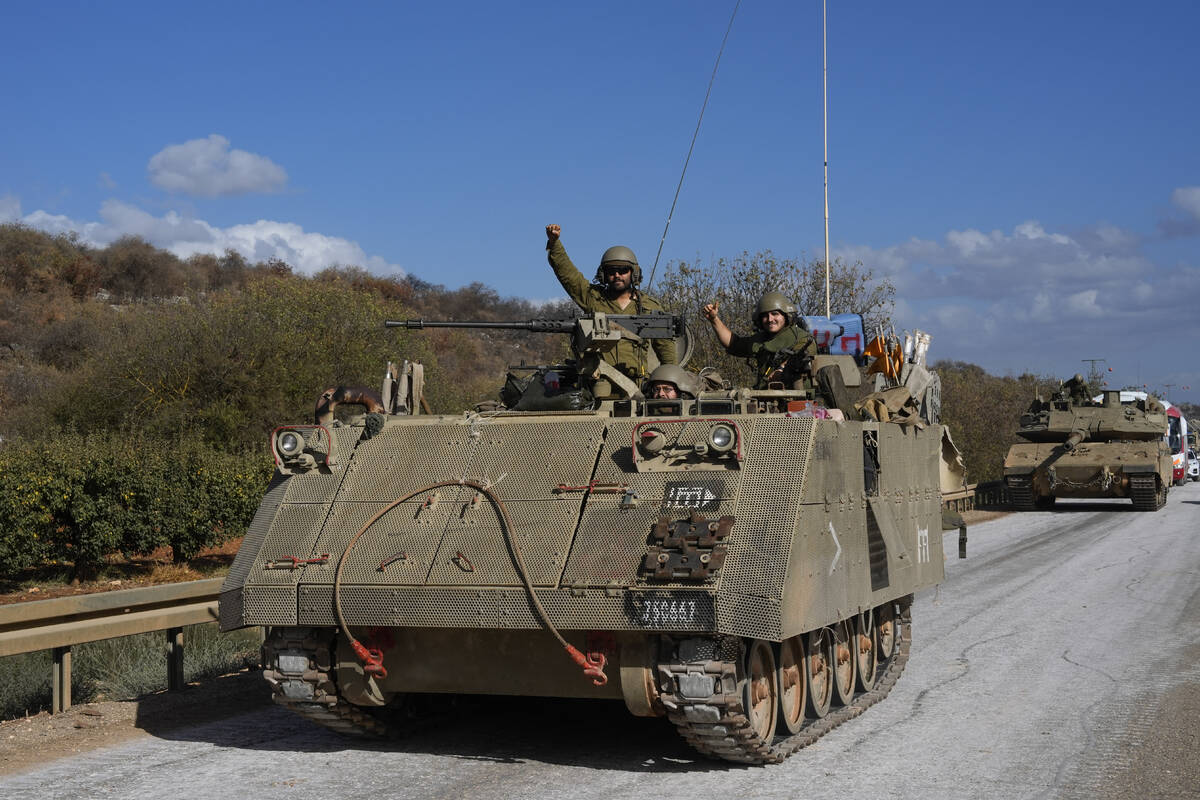 Israeli soldiers raise their fists from a moving APC in northern Israel near the Israel-Lebanon ...