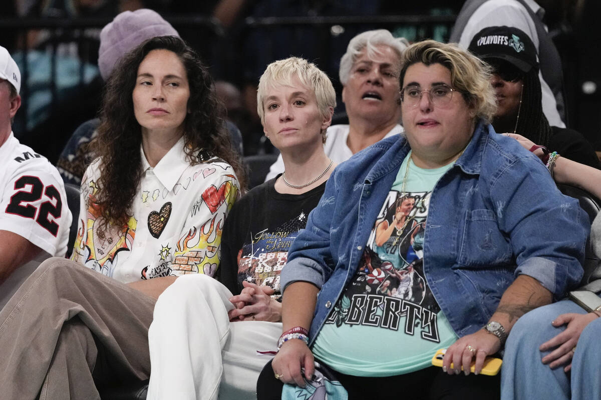 Megan Rapinoe, center, and Sue Bird, left, watch during the second half of a WNBA basketball se ...