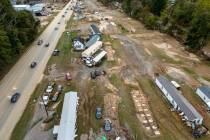 Homes and vehicles that were damaged in a flash flood from Hurricane Helene lie on the side of ...