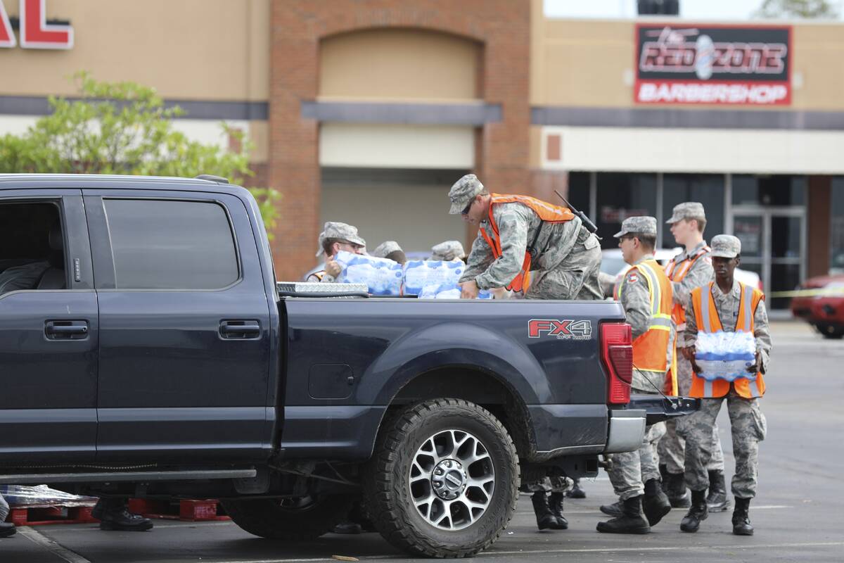 Members of the Civil Air Patrol load water for Hurricane Helene relief into a pickup truck at a ...