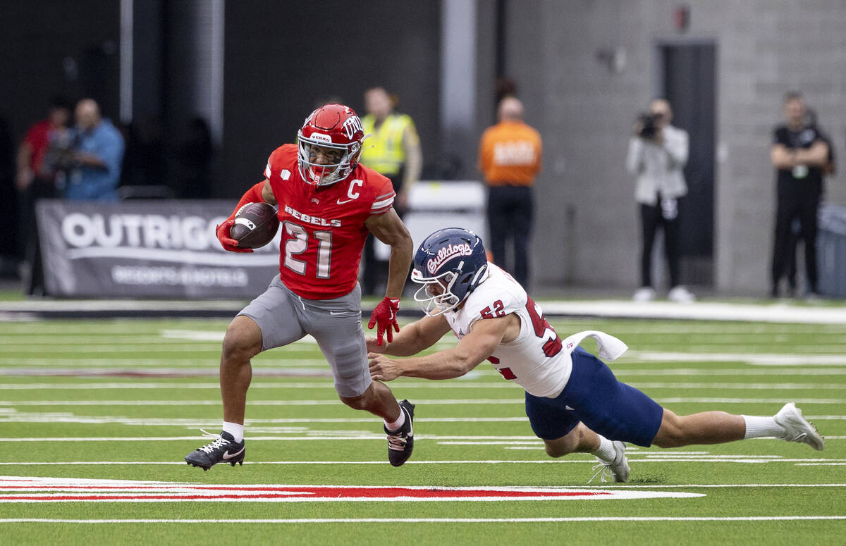 UNLV wide receiver Jacob De Jesus (21) avoids Fresno State defensive lineman Isiah Chala Jr. (5 ...