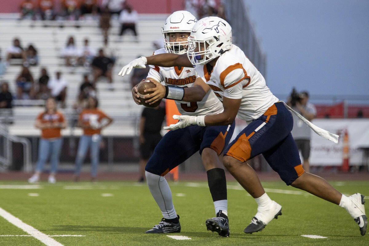 Legacy quarterback Aidan Crawford (9) fakes a handoff to halfback Zaione Henderson (5) during t ...