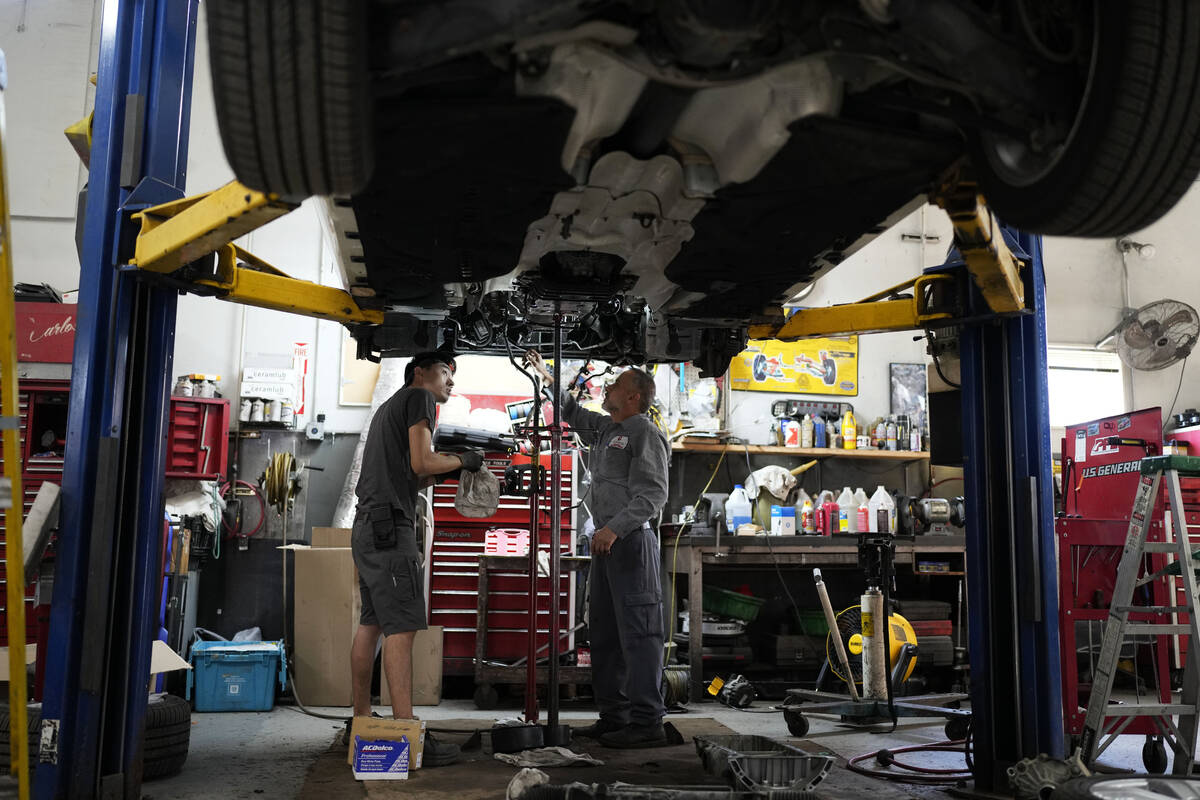 FILE - Auto mechanics work on a vehicle at the Express Auto Service Inc., in Chicago, Sept. 19, ...