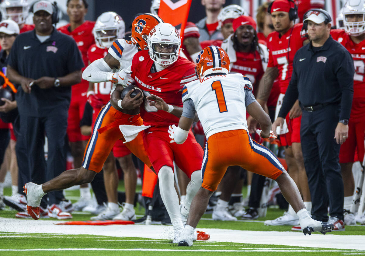 UNLV quarterback Hajj-Malik Williams (6) looks to shake off a tackle on a run against Syracuse ...