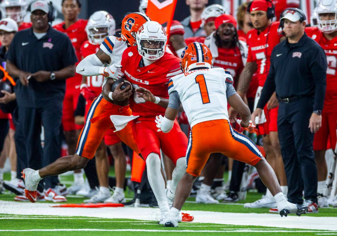 UNLV quarterback Hajj-Malik Williams (6) looks to shake off a tackle on a run against Syracuse ...