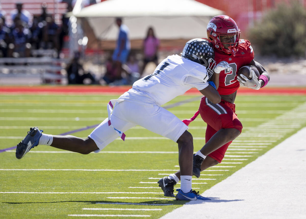 Desert Pines senior Ejuan Carter (1) pushes Arbor View running back Sean Moore (2) out of bound ...