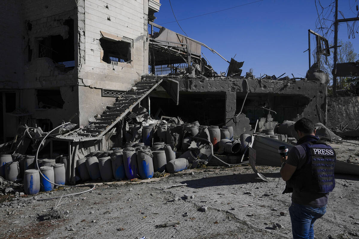 A journalist documents the damaged buildings at the site of an Israeli airstrike, in the villag ...