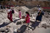 People carry their luggage as they cross into Syria on foot, through a crater caused by Israeli ...