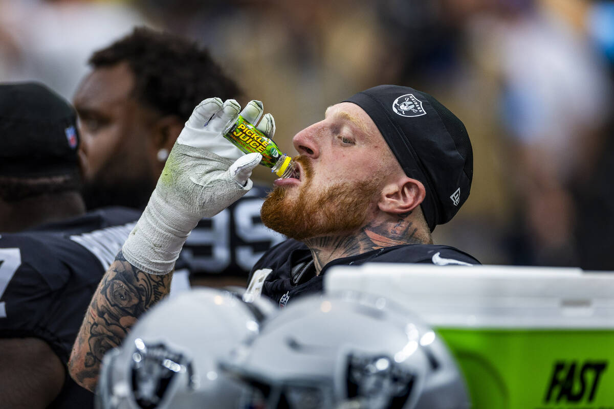 Raiders defensive end Maxx Crosby (98) drinks a bottle of Pickle Juice on the bench against the ...