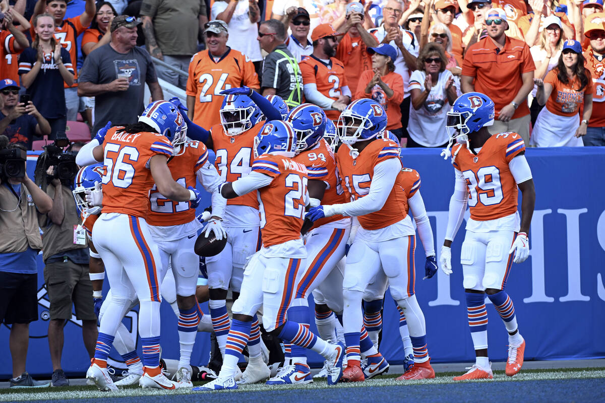 Teammates surround Denver Broncos cornerback Riley Moss (21) after his interception intended fo ...