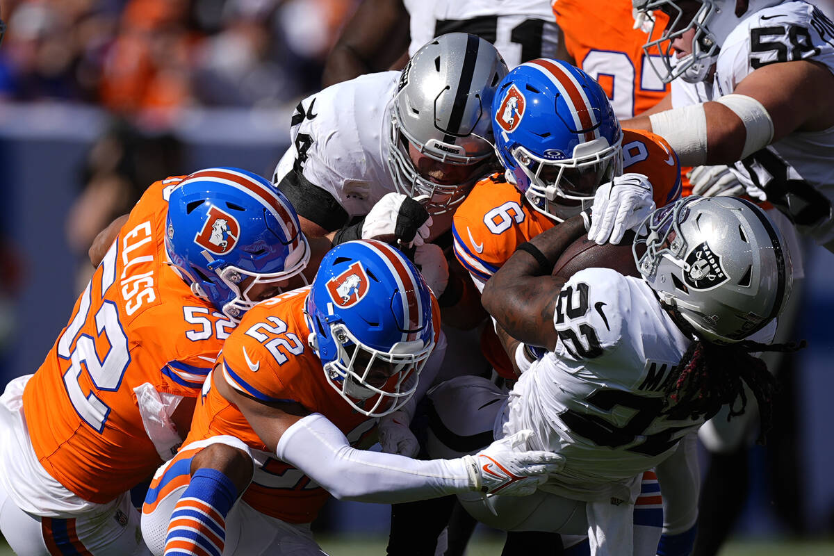 Las Vegas Raiders running back Alexander Mattison (22) is tackled by Denver Broncos safety P.J. ...