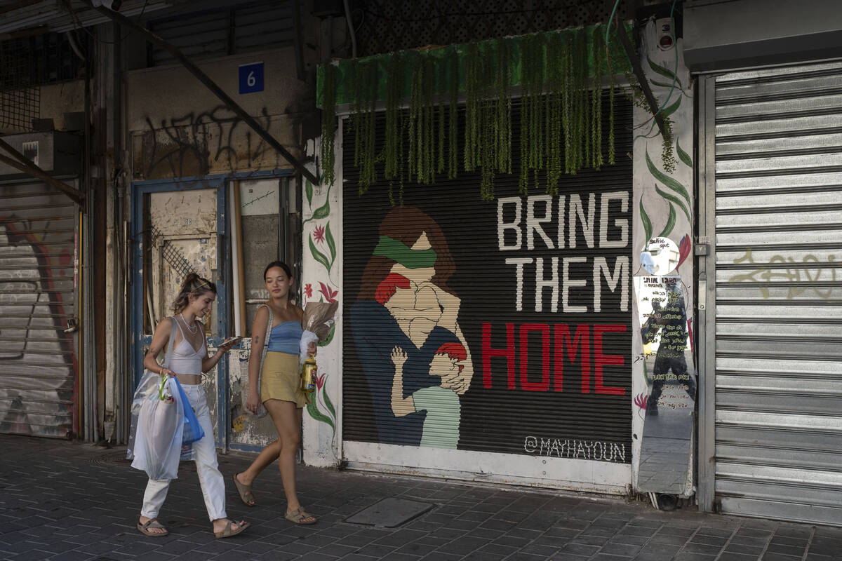 Women walk past graffiti calling for the release of hostages held by Hamas militants in the Gaz ...