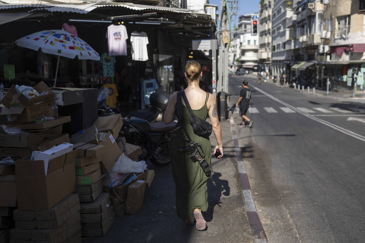 An off-duty Israeli soldier carrying her M-16 rifle walks down the street in Tel Aviv Israel, F ...