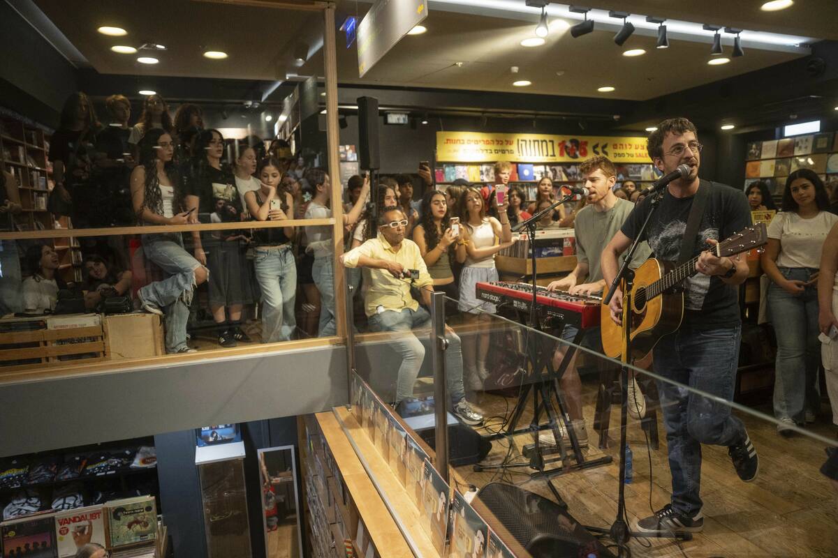 People listen to Israeli singer Yoni Bloch, who has written new songs about the current war, in ...