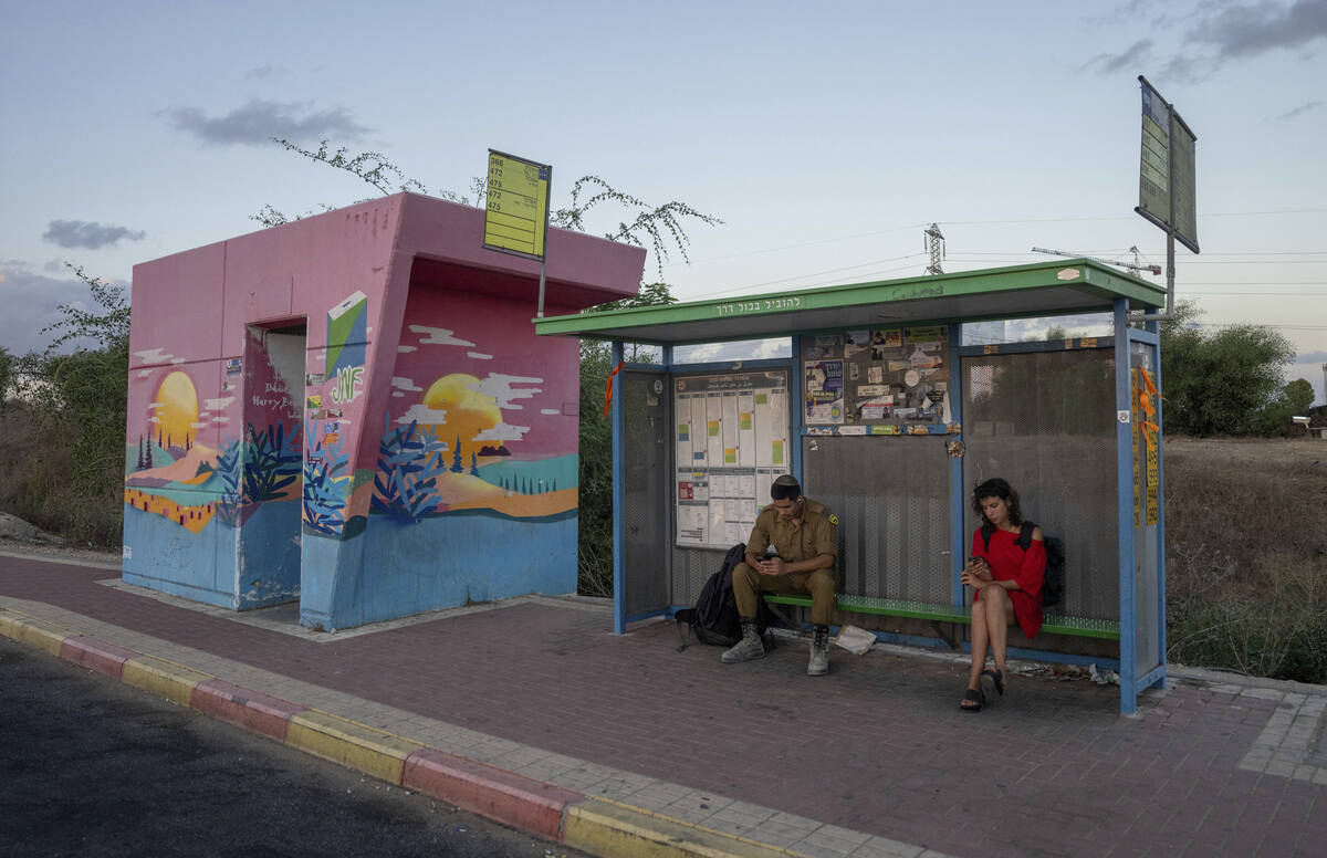 A soldier and a woman wait at a bus stop next to a bomb shelter in the town of Sderot, southern ...