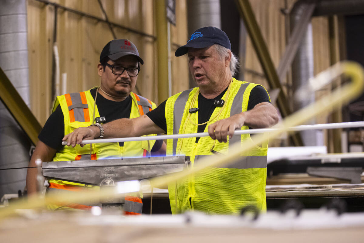 Todd Fisher, right, heats up a neon tube before bending it with guidance from YESCO neon bender ...