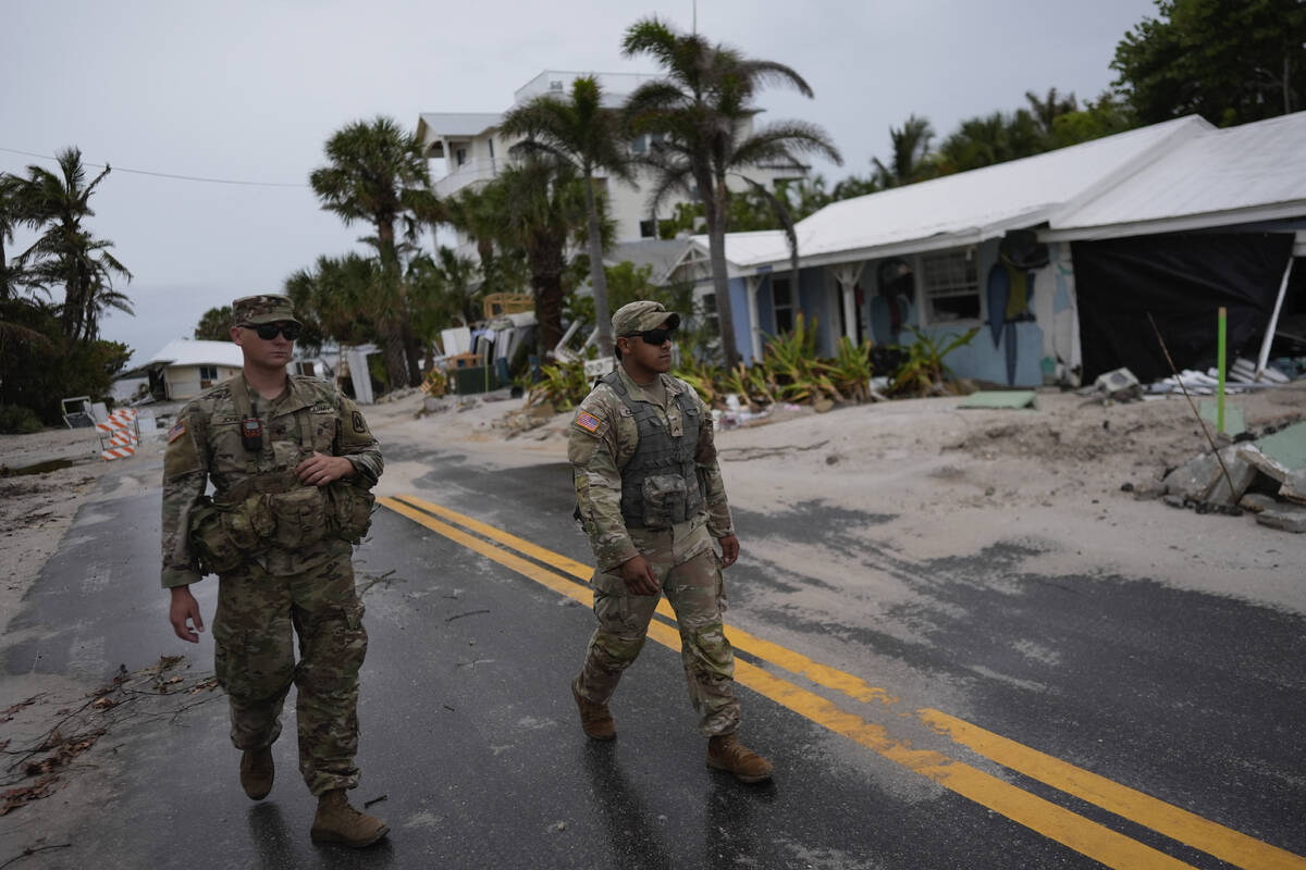 Members of the Florida Army National Guard walk past a home slated for demolition after being d ...