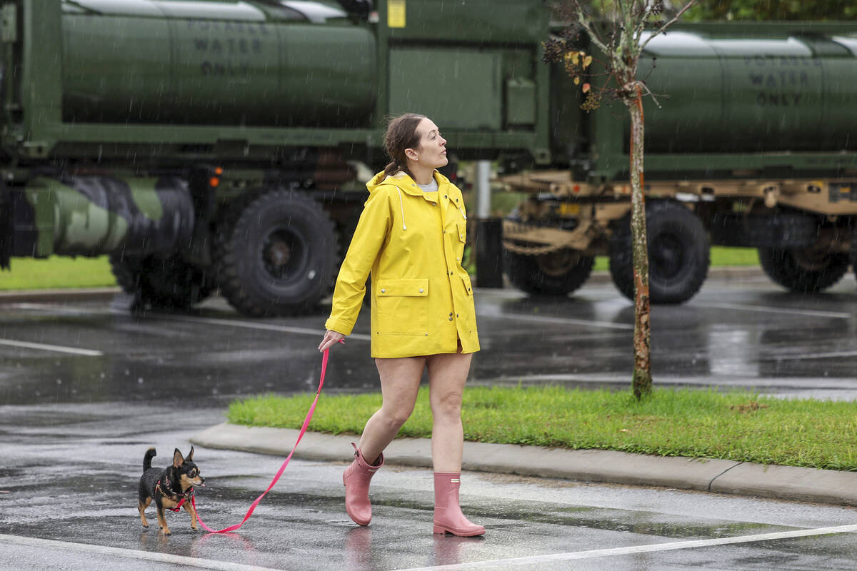 Erin Ferguson walks her dog while looking at equipment stationed by the Florida National Guard ...