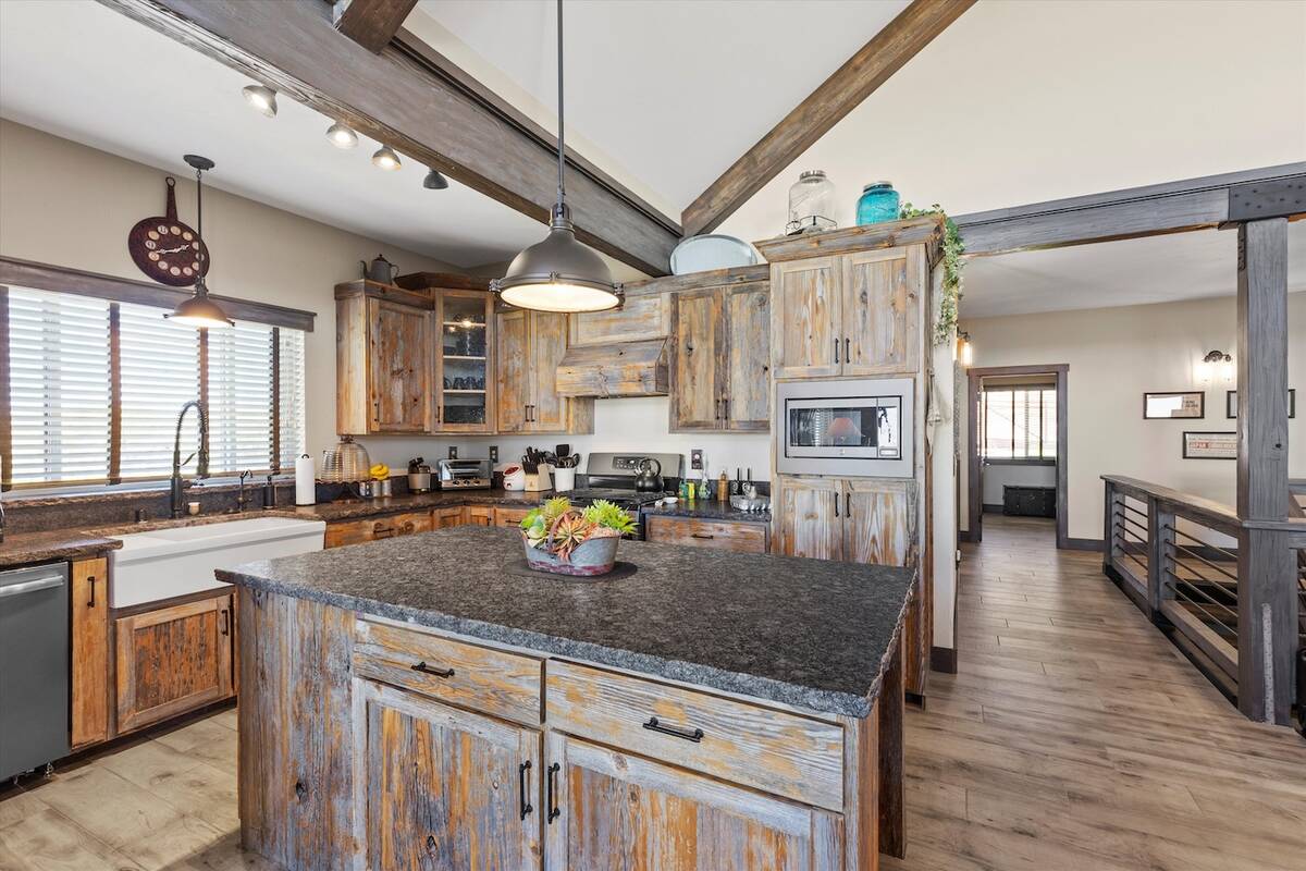 The kitchen features a wood-encased range hood and porcelain farm sink. (Avia Media Group)