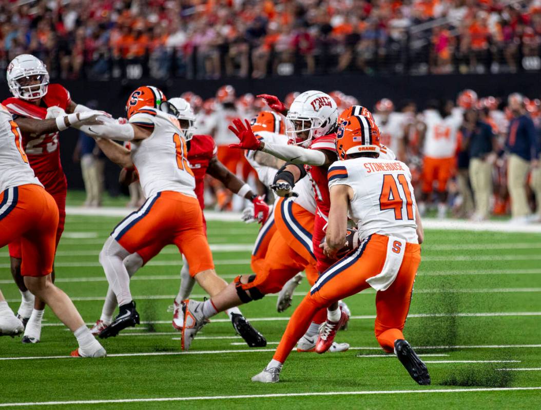 UNLV wide receiver Ricky White III (11) disrupts Syracuse Orange punter Jack Stonehouse (41) fr ...