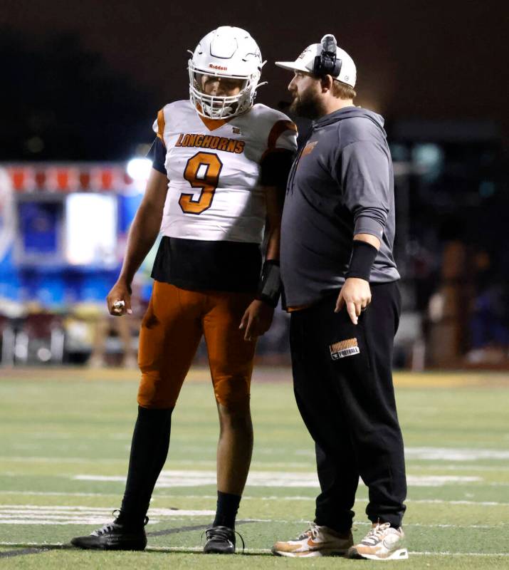 Legacy High's head coach Zach Monticelli consults with quarterback Aidan Crawford (9) during th ...