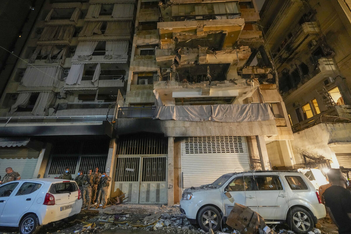 Soldiers stand guard under a building hit by an Israeli airstrike in Beirut, Lebanon, Thursday, ...