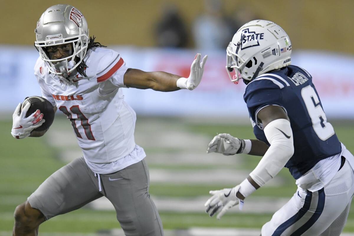 UNLV wide receiver Ricky White III (11) runs downfield as Utah State safety Ike Larsen (6) defe ...