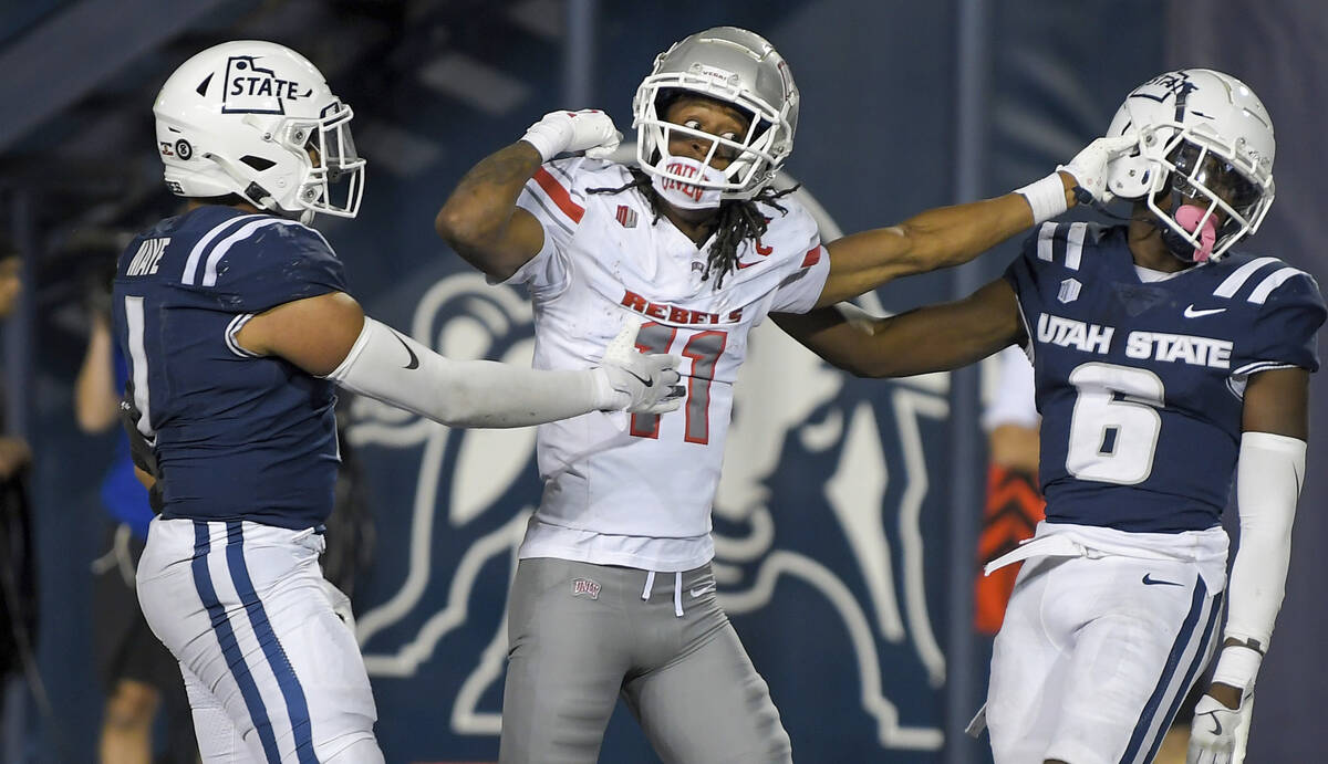 UNLV wide receiver Ricky White III (11) gets tangled up with Utah State safety Ike Larsen (6) i ...