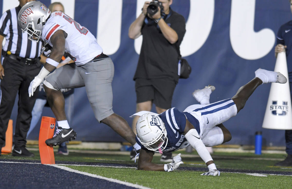 UNLV running back Kylin James, left, runs over Utah State safety Ike Larsen, right, to score a ...