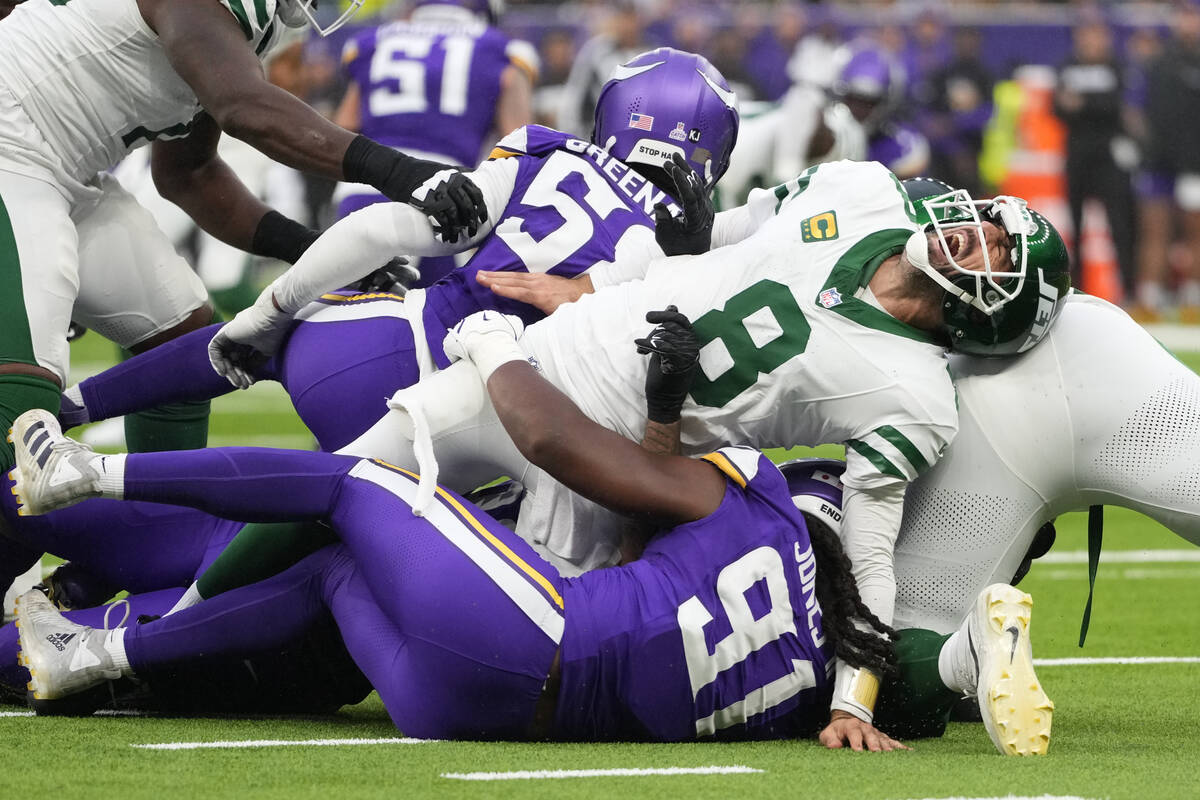 New York Jets quarterback Aaron Rodgers (8), right, reacts as he is tackled during the second h ...