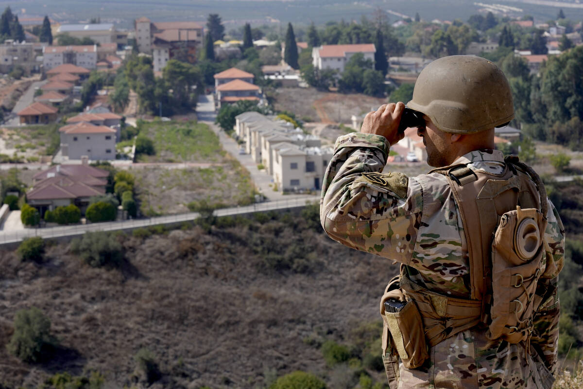 FILE - A Lebanese soldier looks through his binoculars into the Israeli town of Metula at the L ...