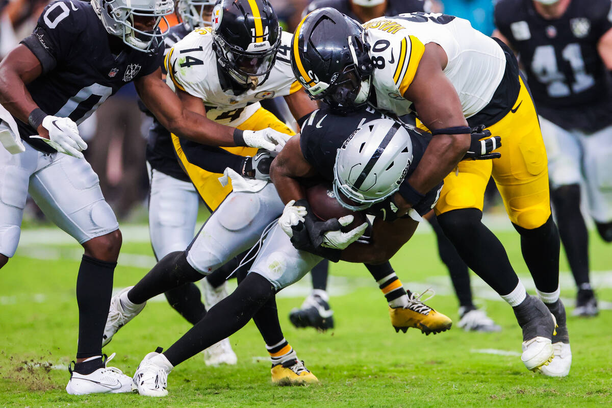 Raiders linebacker Divine Deablo (5) keeps the ball in his grip as Pittsburgh Steelers tight en ...