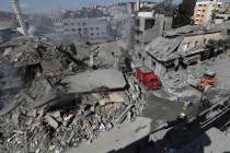 Hezbollah rescue workers use a bulldozer to remove the rubble of destroyed buildings on a comme ...