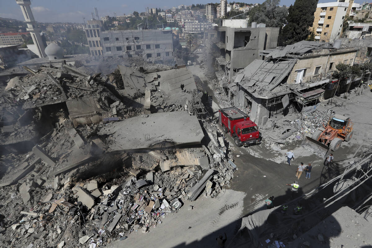 Hezbollah rescue workers use a bulldozer to remove the rubble of destroyed buildings on a comme ...