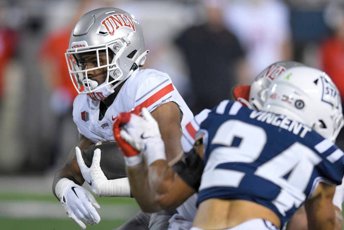 UNLV running back Kylin James, left, carries the ball as Utah State safety Jordan Vincent (24) ...