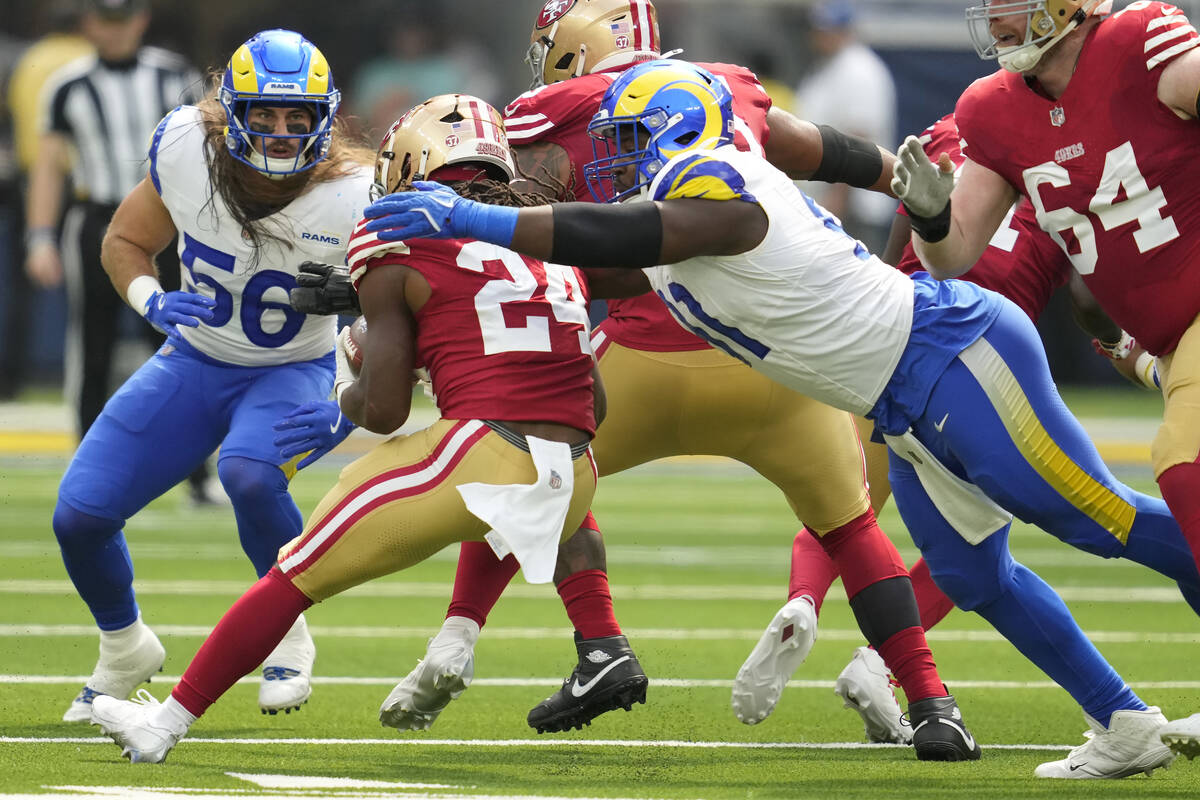 Los Angeles Rams defensive tackle Kobie Turner, right, reaches to tackle San Francisco 49ers ru ...