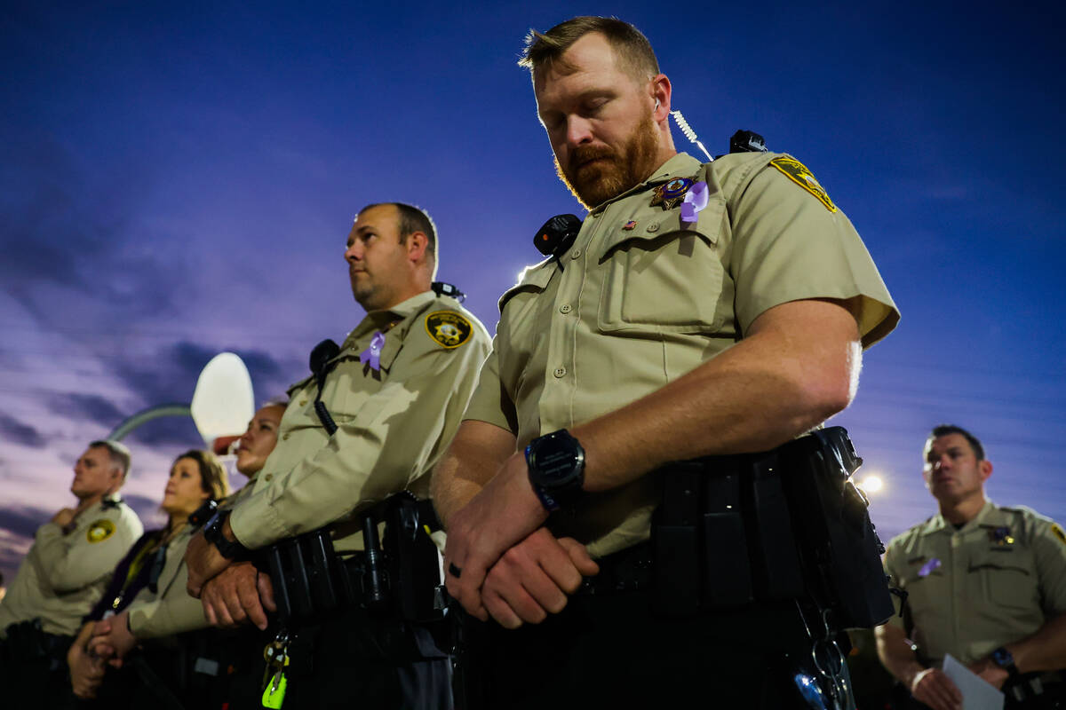 Police officers take in a moment of reflection during a tree dedication ceremony in honor of vi ...