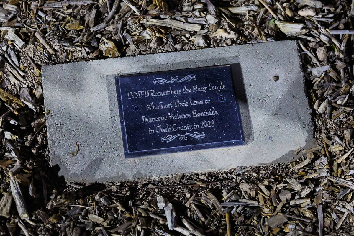 A plaque beneath a tree is seen during a tree dedication ceremony in honor of victims of domest ...