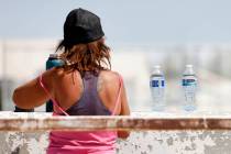 A homeless person fills up her water bottle, delivered by a Help of Southern Nevada outreach wo ...