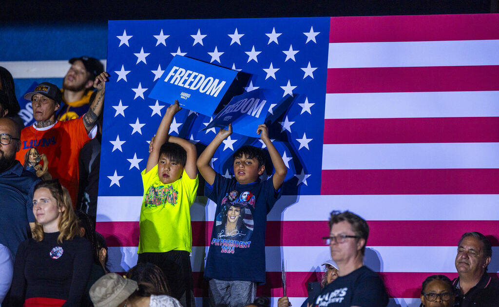 Youngsters hold up signs as Former President Barack Obama speaks on behalf of the Harris-Walz c ...