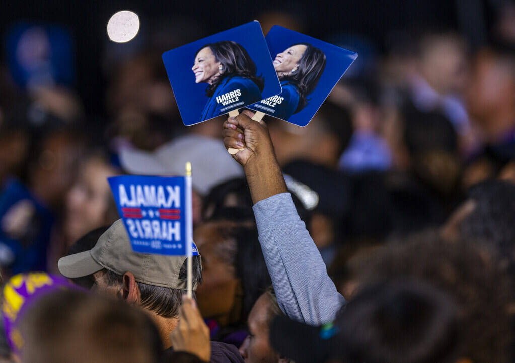 The crowd holds up signs and flags as Former President Barack Obama speaks on behalf of the Har ...