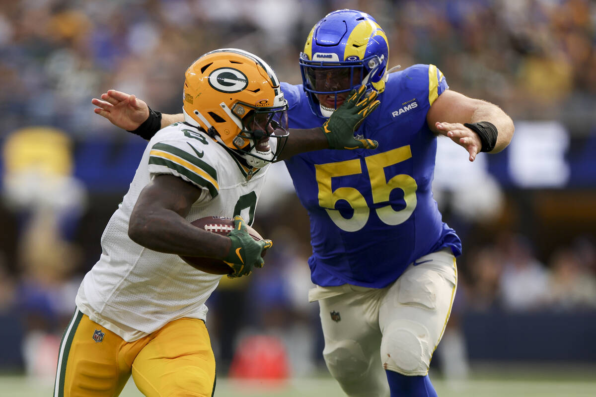 Green Bay Packers running back Josh Jacobs, left, stiff arms Los Angeles Rams defensive tackle ...